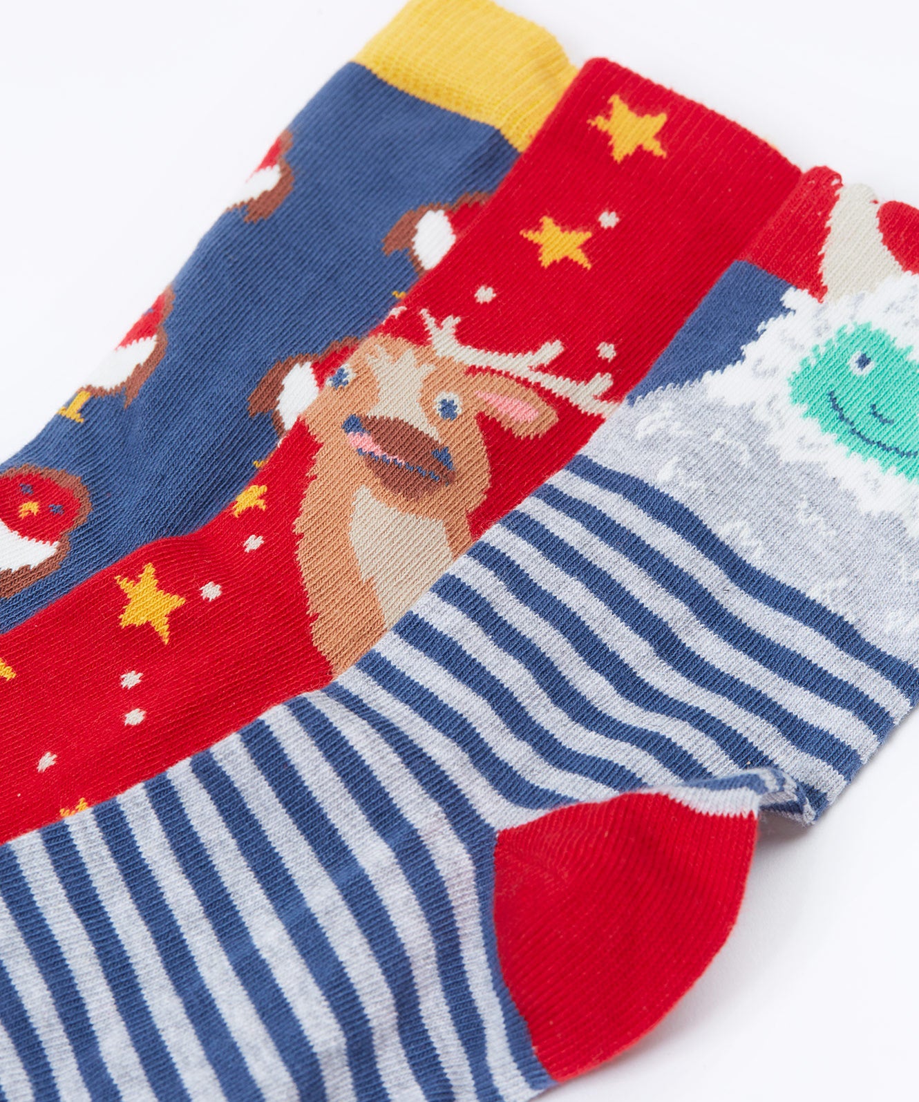 A close up of the Frugi rock my socks 3 in festive multipack available at Babipur. GOTS socks in 3 different designs including a striped with a yeti, a red with reindeer and a blue sock with a cute robin design.