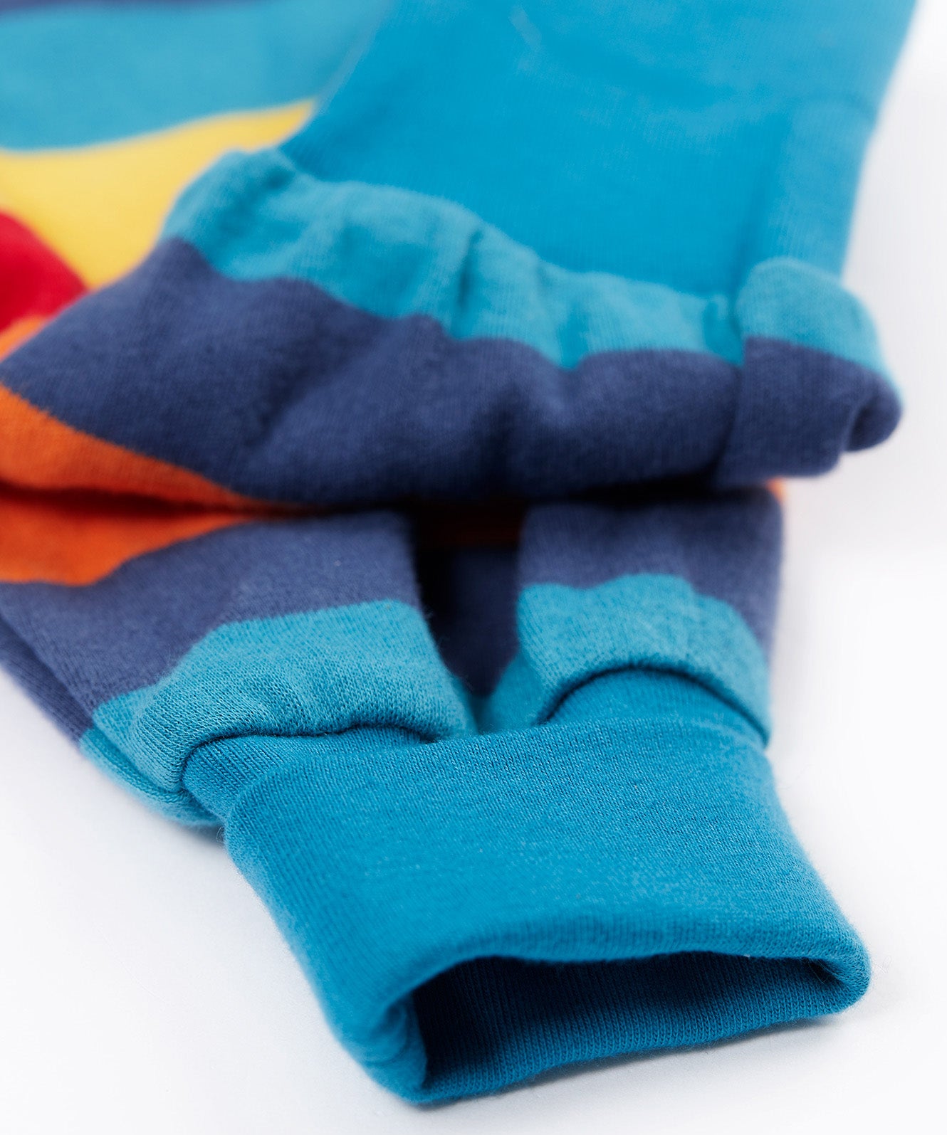 A close up of the leg cuffs on the Frugi parsnip pants in big rainbow stripe available at Babipur. A GOTS organic cotton bottom in bold rainbow inspired striped design. Features blue elasticated cuffs