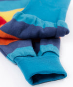 A close up of the leg cuffs on the Frugi parsnip pants in big rainbow stripe available at Babipur. A GOTS organic cotton bottom in bold rainbow inspired striped design. Features blue elasticated cuffs