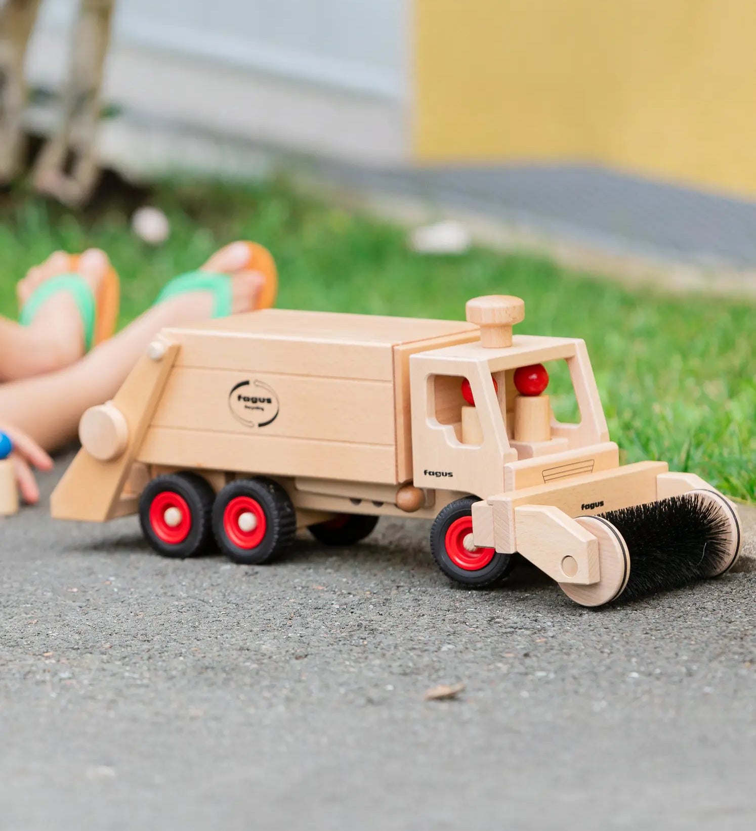 Wooden Fagus garbage tipper toy with two peg dolls and sweeper attachment.