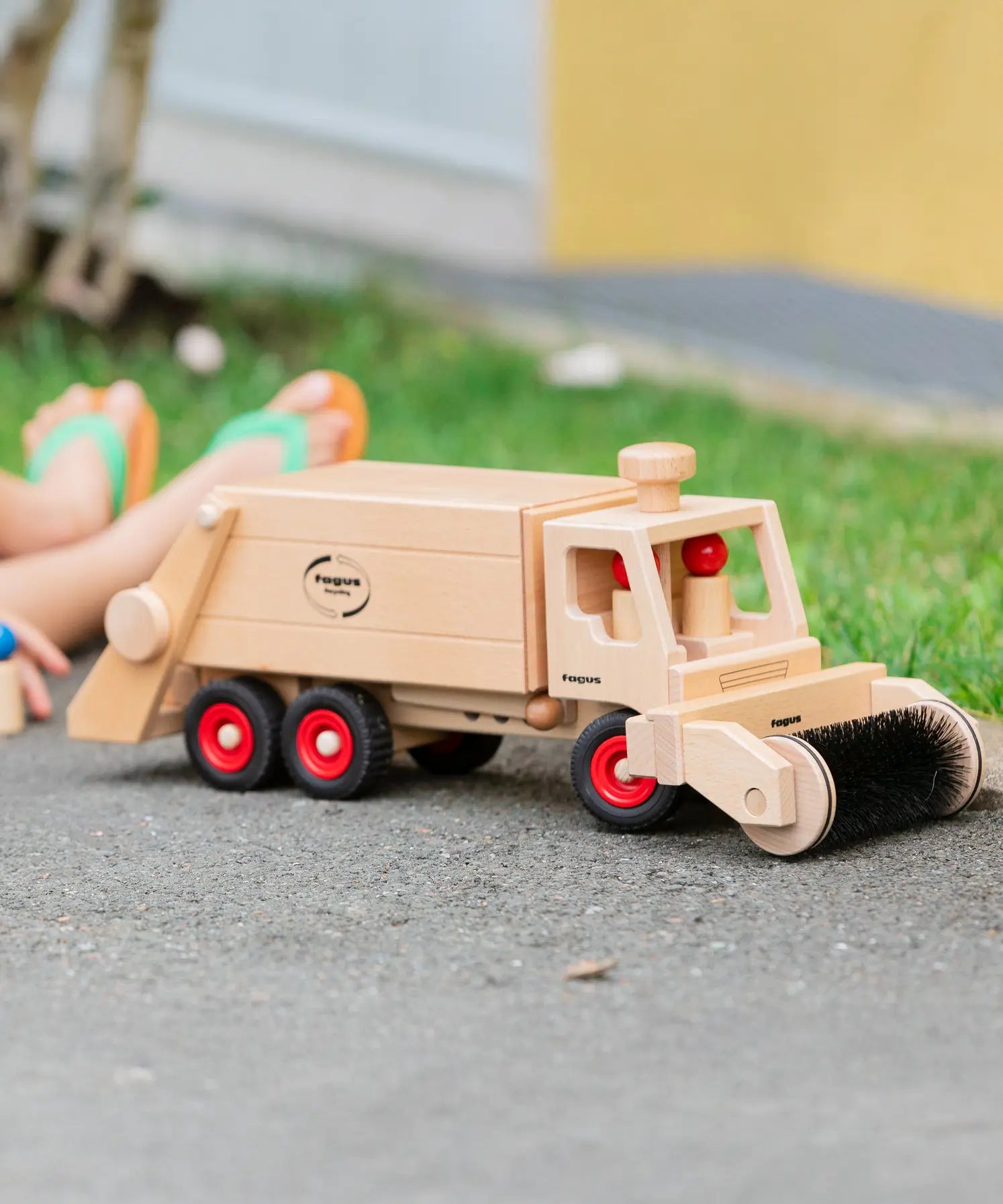 Wooden Fagus garbage tipper toy with two peg dolls and sweeper attachment.