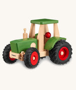 Wooden toy tractor with green body, black wheels, and red details on a white background