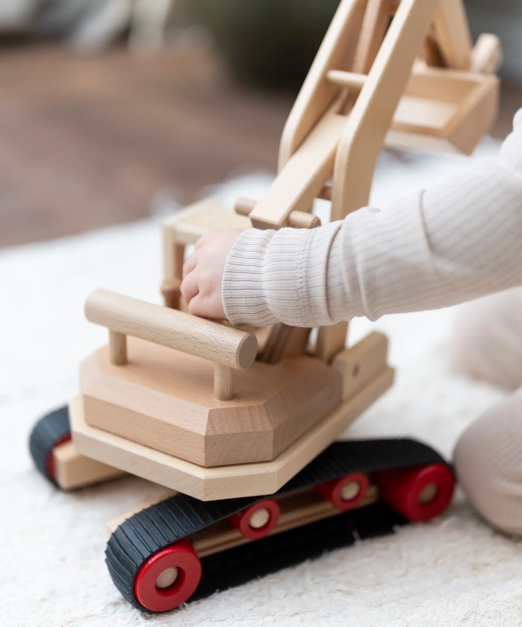 Fagus excavator toy, beautifully handmade from wood with grippy rubber tracks, an adjustable scoop and two peg dolls for small world play.