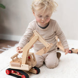 Fagus excavator wooden toy featuring grippy rubber tracks, an adjustable scoop and two peg dolls, perfect for small world play.