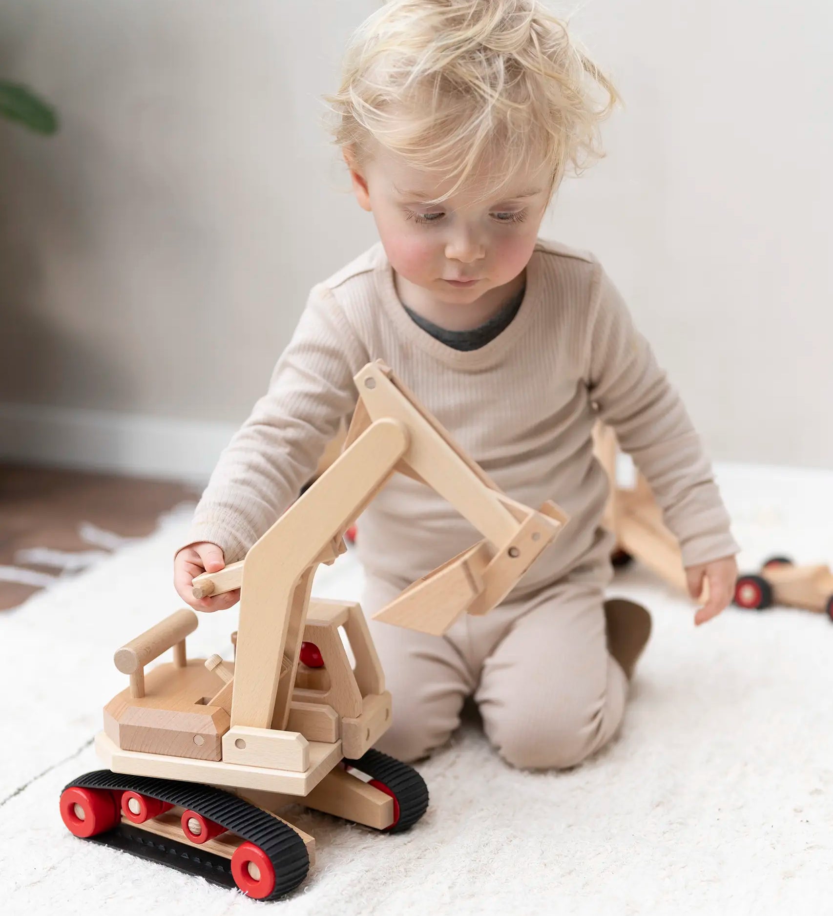 Fagus excavator wooden toy featuring grippy rubber tracks, an adjustable scoop and two peg dolls, perfect for small world play.