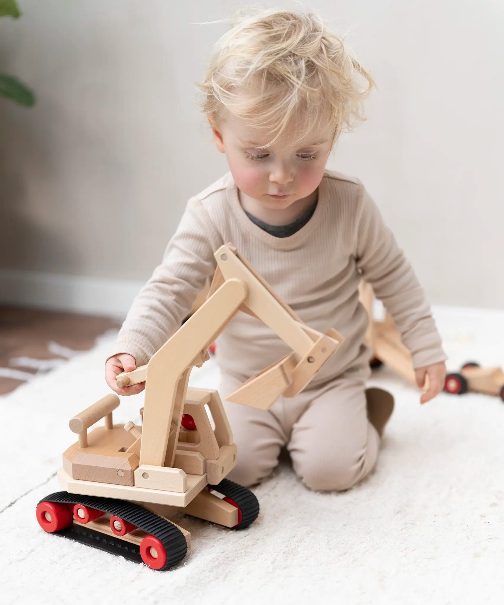 Fagus excavator wooden toy featuring grippy rubber tracks, an adjustable scoop and two peg dolls, perfect for small world play.
