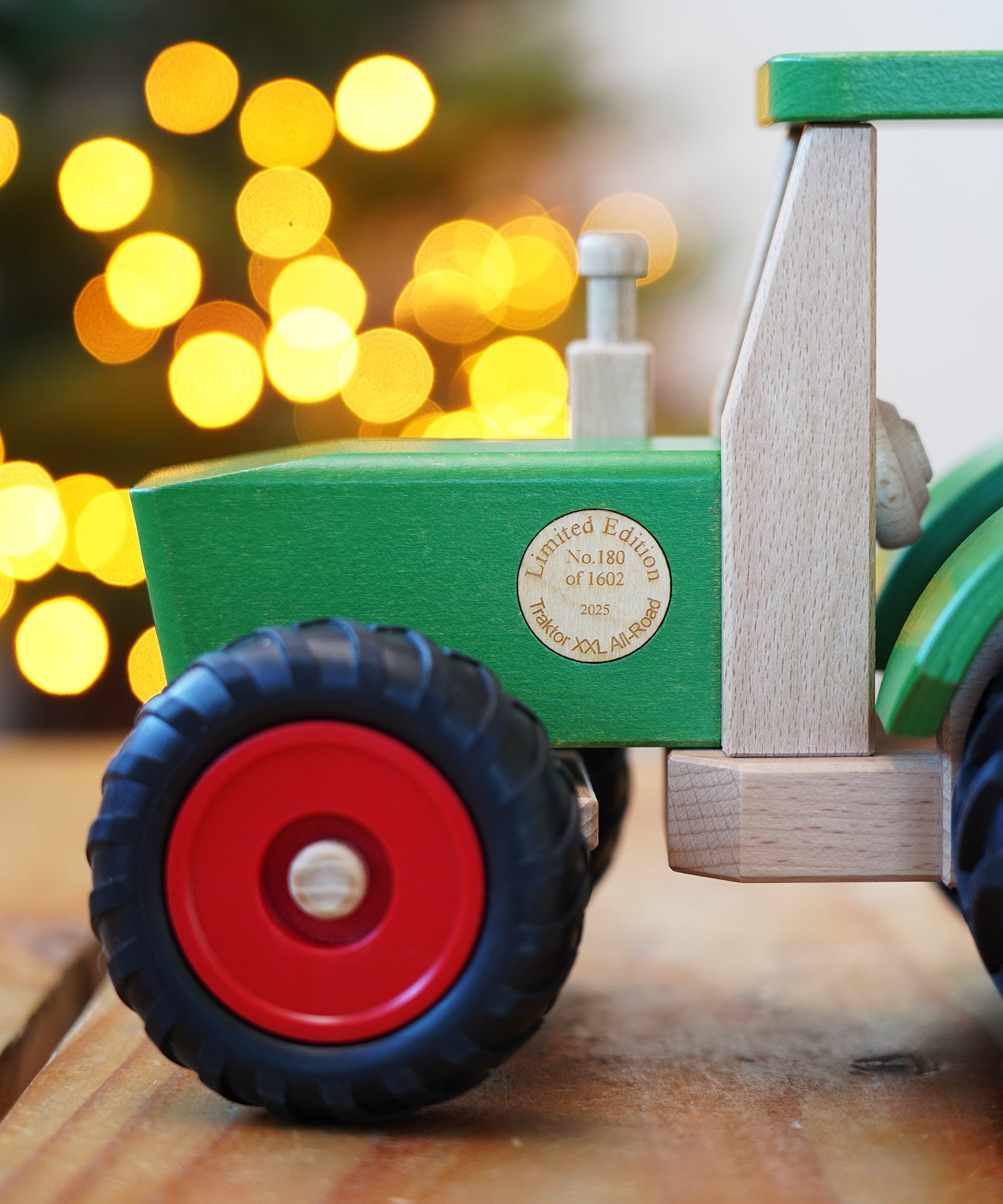 Wooden toy truck with red wheels on a wooden surface, blurred lights in the background