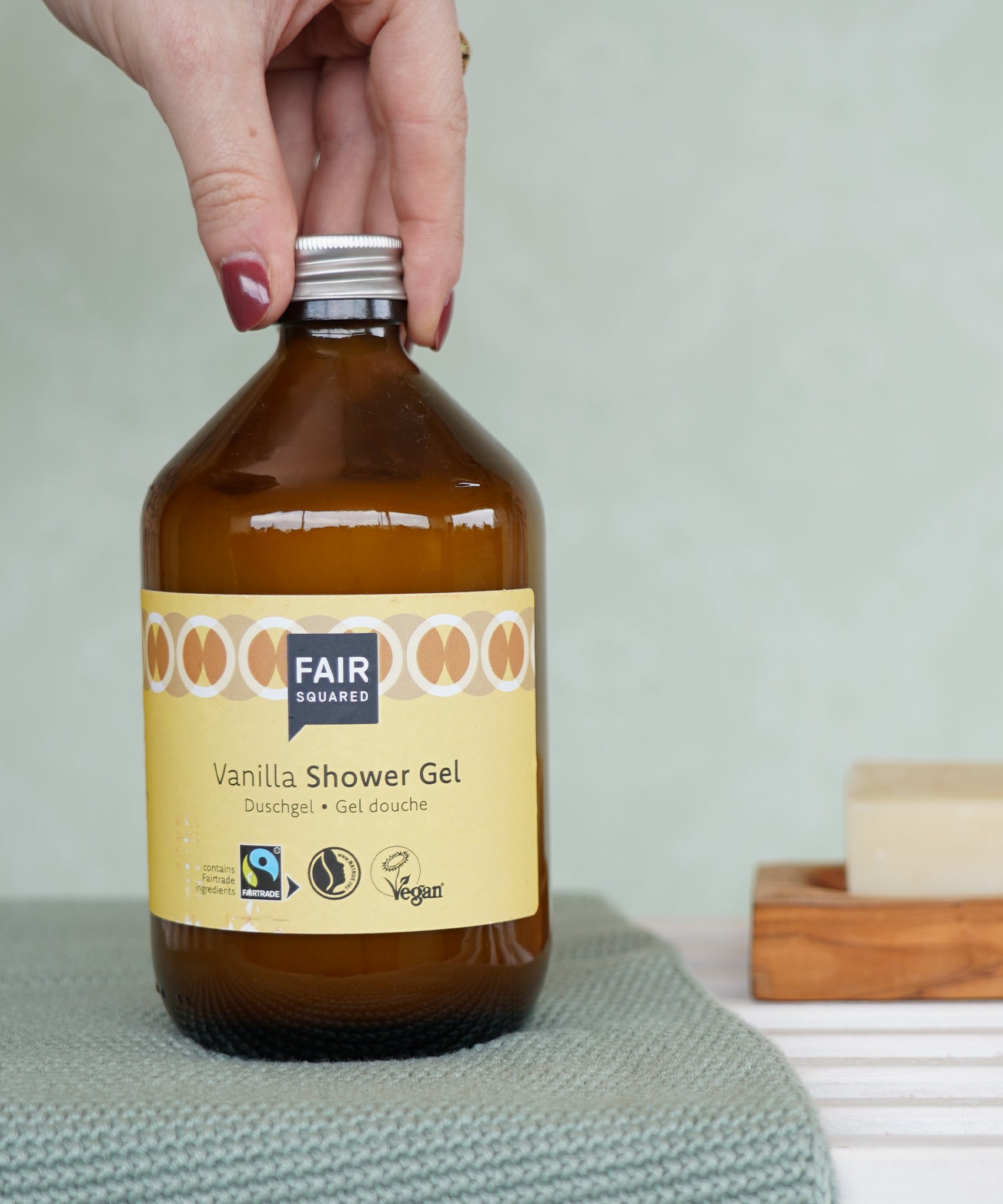 A glass bottle of Fair Squared Fairtrade Vanilla Shower Gel 500ml in a bathroom - vegan, cruelty free and plastic free - for sale at Babipur.