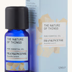 Frankincense pure essential oil in a blue glass bottle in front of a decorative blue cardboard box.