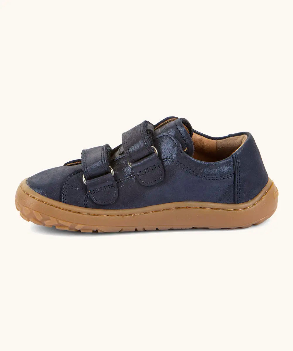 Side of Froddo barefoot base children's shoe in blue showing the 2 velcro fasteners looped through and the brown grippy sole