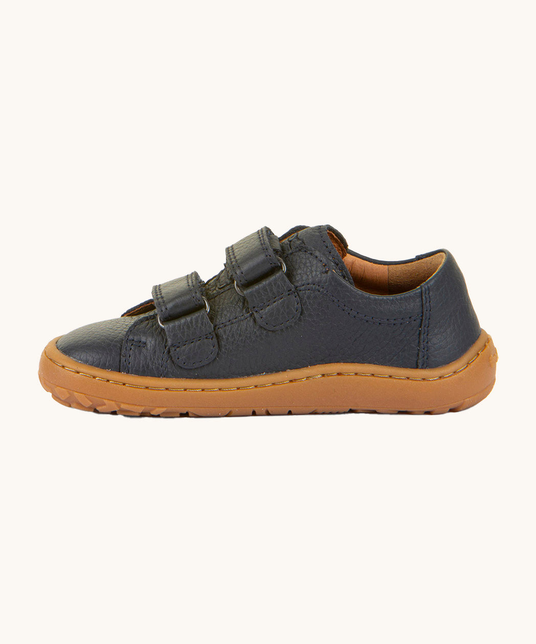 A side image of the Froddo barefoot base children's shoe in navy available at Babipur. A dark turquoise natural leather low profile shoe showing the 2 velcro fasteners looped through and the brown grippy sole