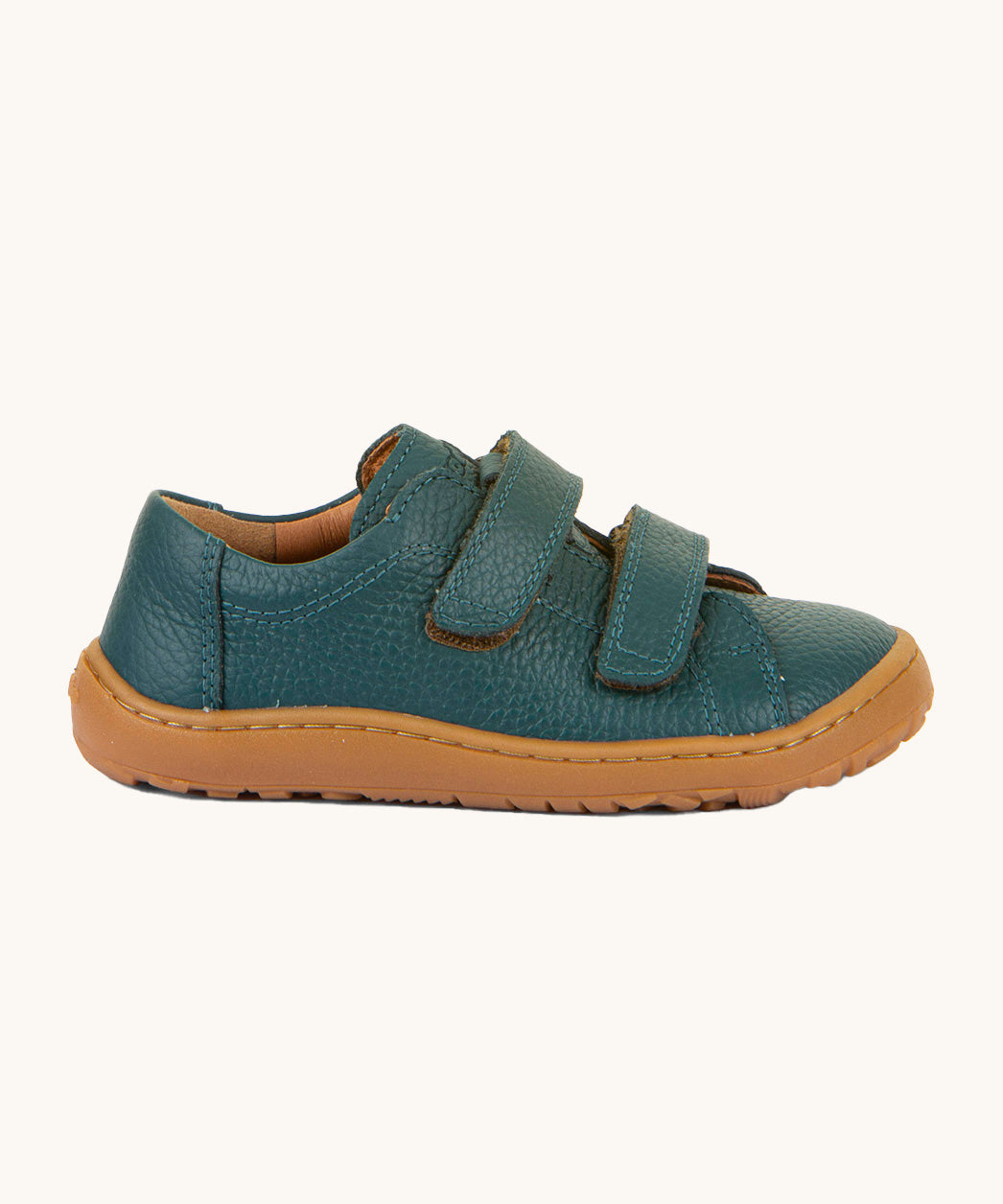 A side image of the Froddo barefoot base children's shoe in petroleum available at Babipur. A dark turquoise natural leather low profile shoe showing the 2 velcro fasteners and the brown grippy sole