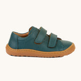 A side image of the Froddo barefoot base children's shoe in petroleum available at Babipur. A dark turquoise natural leather low profile shoe showing the 2 velcro fasteners and the brown grippy sole