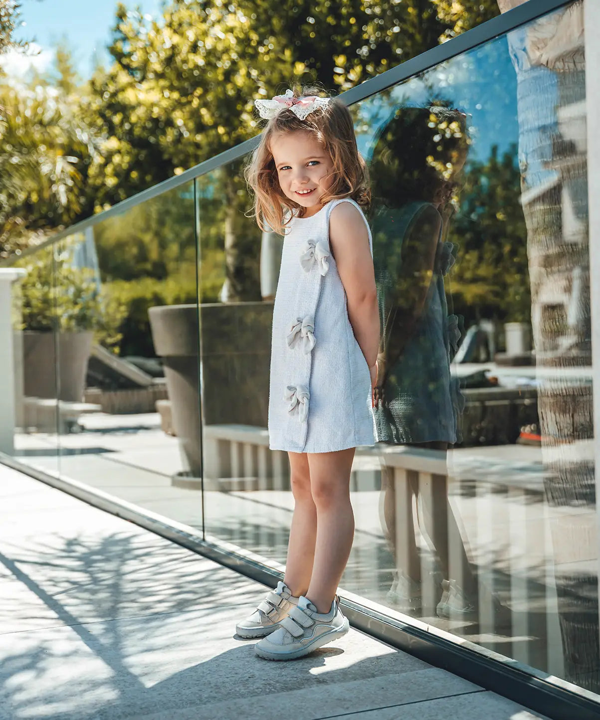 Child wearing Froddo's barefoot base children's shoe with velcro straps in white and standing on a concrete surface
