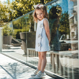 Child wearing Froddo's barefoot base children's shoe with velcro straps in white and standing on a concrete surface