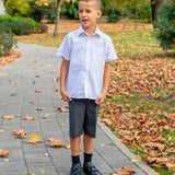 Child wearing Froddo's natural black leather barefoot school shoes standing on a concrete path in a park