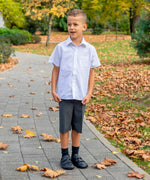 Child wearing Froddo's natural black leather barefoot school shoes standing on a concrete path in a park