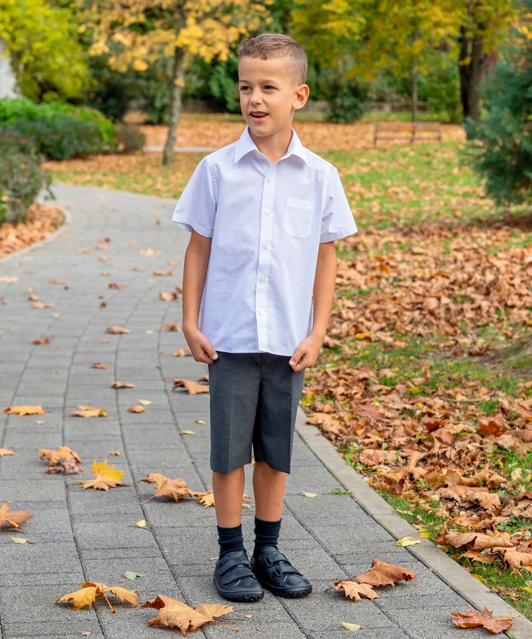 Child wearing Froddo's natural black leather barefoot school shoes standing on a concrete path in a park
