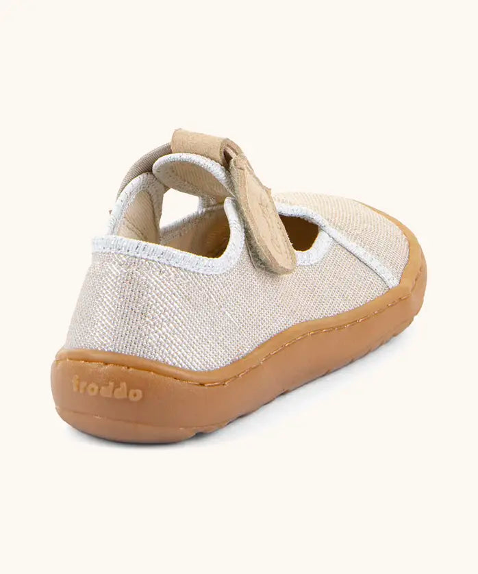 Back of Froddo barefoot canvas style kids shoes in pale cream with a t-bar velcro fastener and brown rubber sole