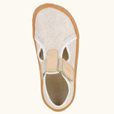 Top view of Froddo barefoot canvas style kids shoes in pale cream with  showing t-bar velcro fastener lopped through the eyelet 