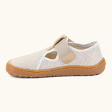 Side of Froddo barefoot canvas style kids shoes in pale cream  showing t-bar velcro fastener lopped through the eyelet 
