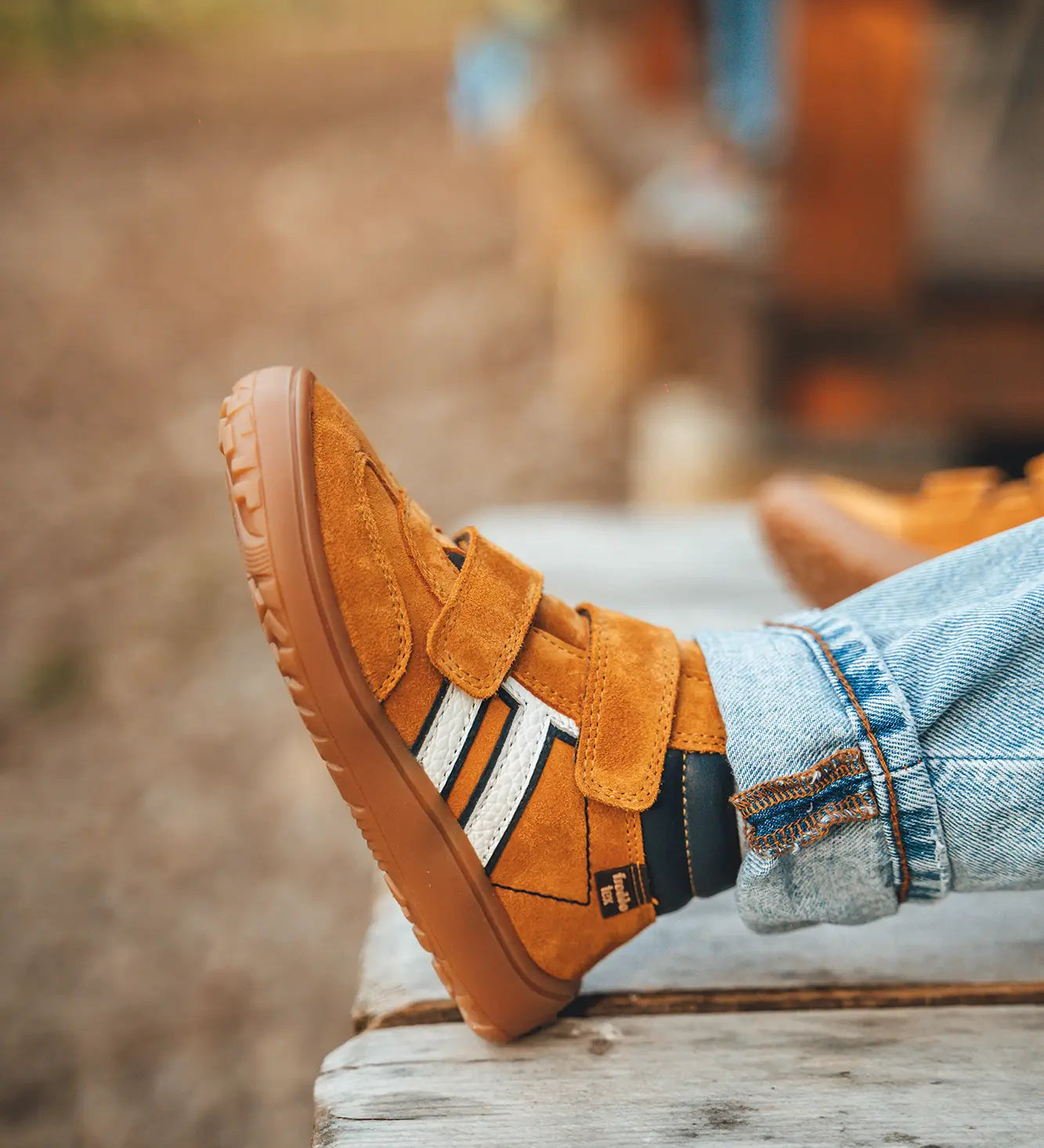 Child wearing Froddo’s Barefoot Kids F-Motion TEX Shoes in mustard with the velcro fully fastened. Boot sits around the upper ankle