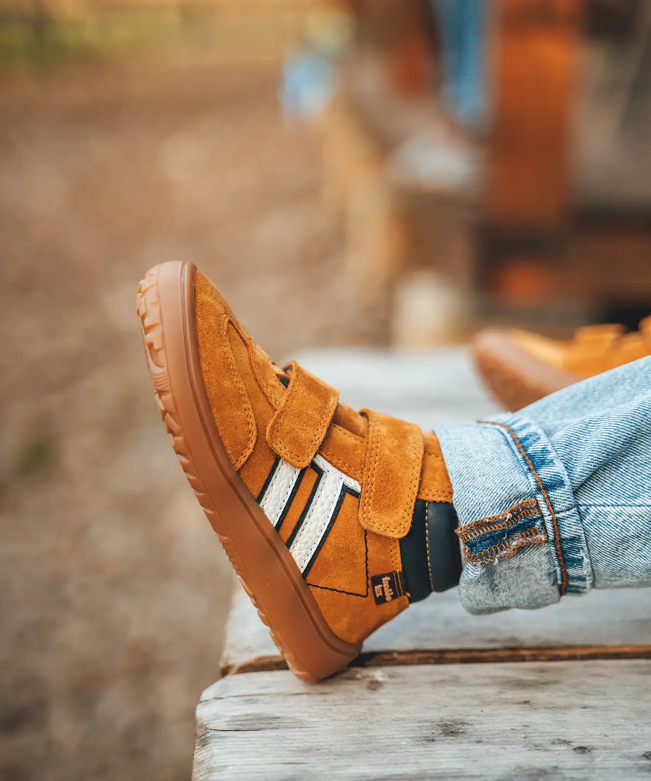 Child wearing Froddo’s Barefoot Kids F-Motion TEX Shoes in mustard with the velcro fully fastened. Boot sits around the upper ankle