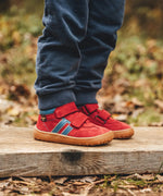 Child wearing Froddo’s Barefoot Kids F-Motion TEX Shoes in red outdoors showing the velcro fully fastened. Boot sits around the upper ankle
