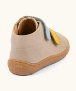 Back of the Froddo barefoot first step baby shoe in beige showing a padded ankle support and grippy sole 