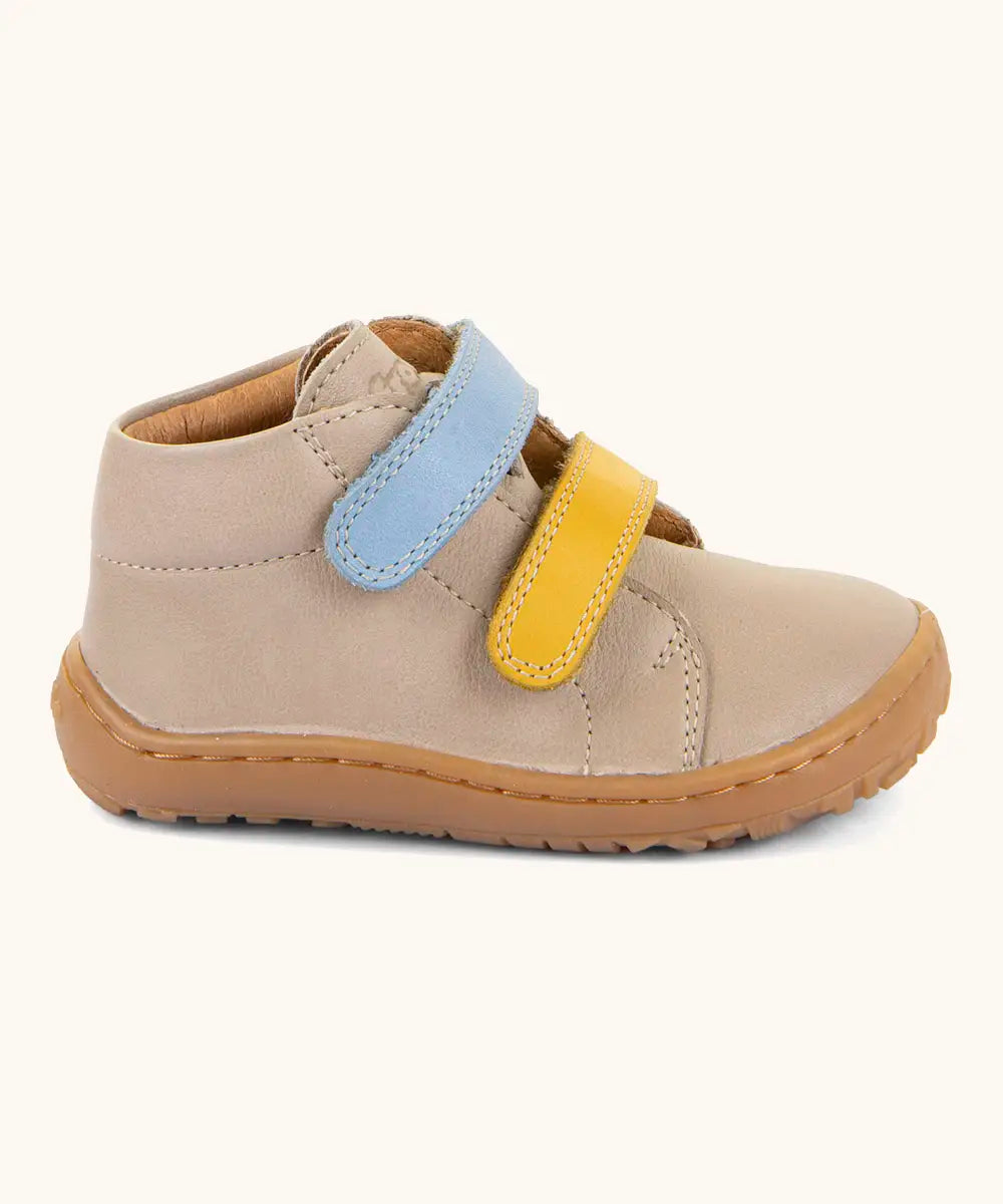 Side of the Froddo barefoot first step baby shoe in dark blue a showing 2 velcro fasteners in blue and yellow