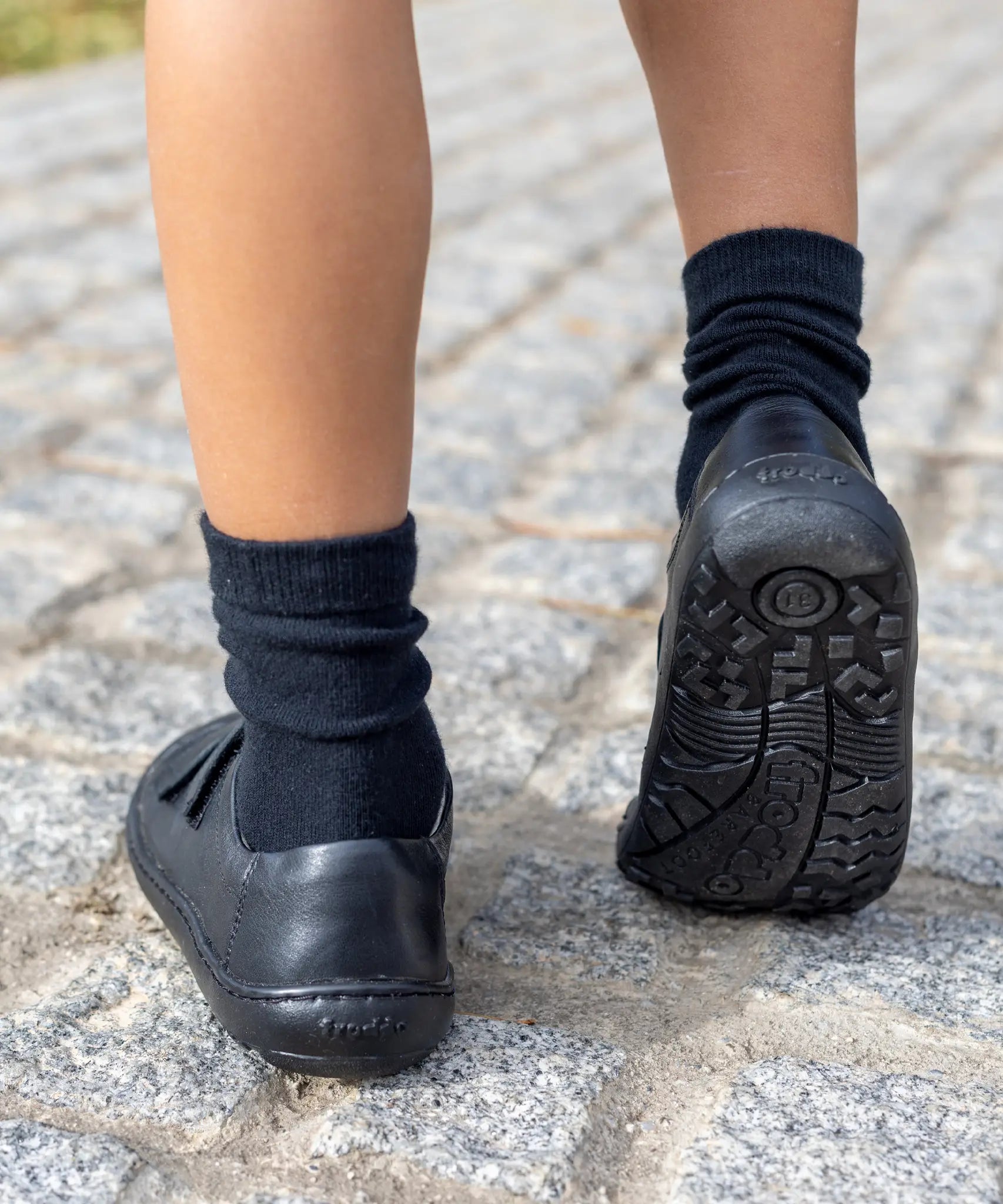 Back of child wearing Froddo's natural black leather barefoot school shoes showing the tread detail on the sole