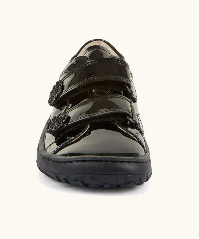 Front of Froddo barefoot kids school shoe in black patent. A low profile shoe showing 2 velcro straps with a decoration on the end
