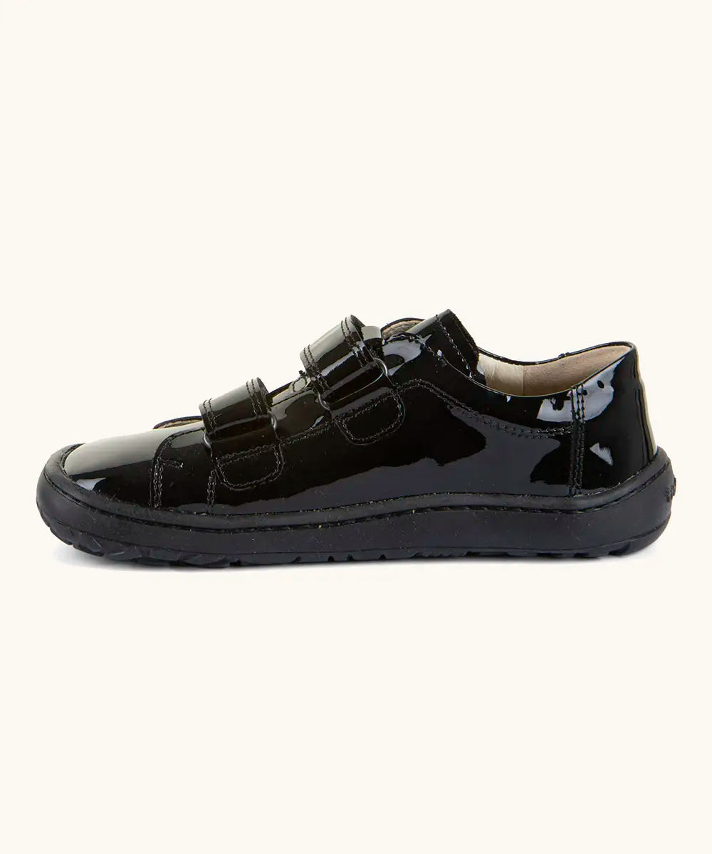 Side of Froddo Alexandra barefoot kids school shoe in black patent showing the velcro straps looped through the eyelets