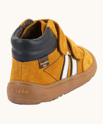 Back of Froddo’s Barefoot Kids F-Motion TEX suede shoes in mustard showing  the navy padded ankle white side stripe and brown rubber sole