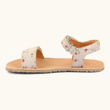 Side of Froddo barefoot kids natural leather sandal in pink with flowers. Showing strap looped through the eyelet on the ankle