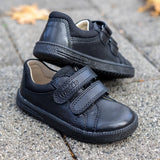 Pair of Froddo barefoot natural leather kids Steve school shoes in black standing on a concrete surface