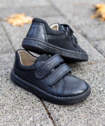 Pair of Froddo barefoot natural leather kids Steve school shoes in black standing on a concrete surface
