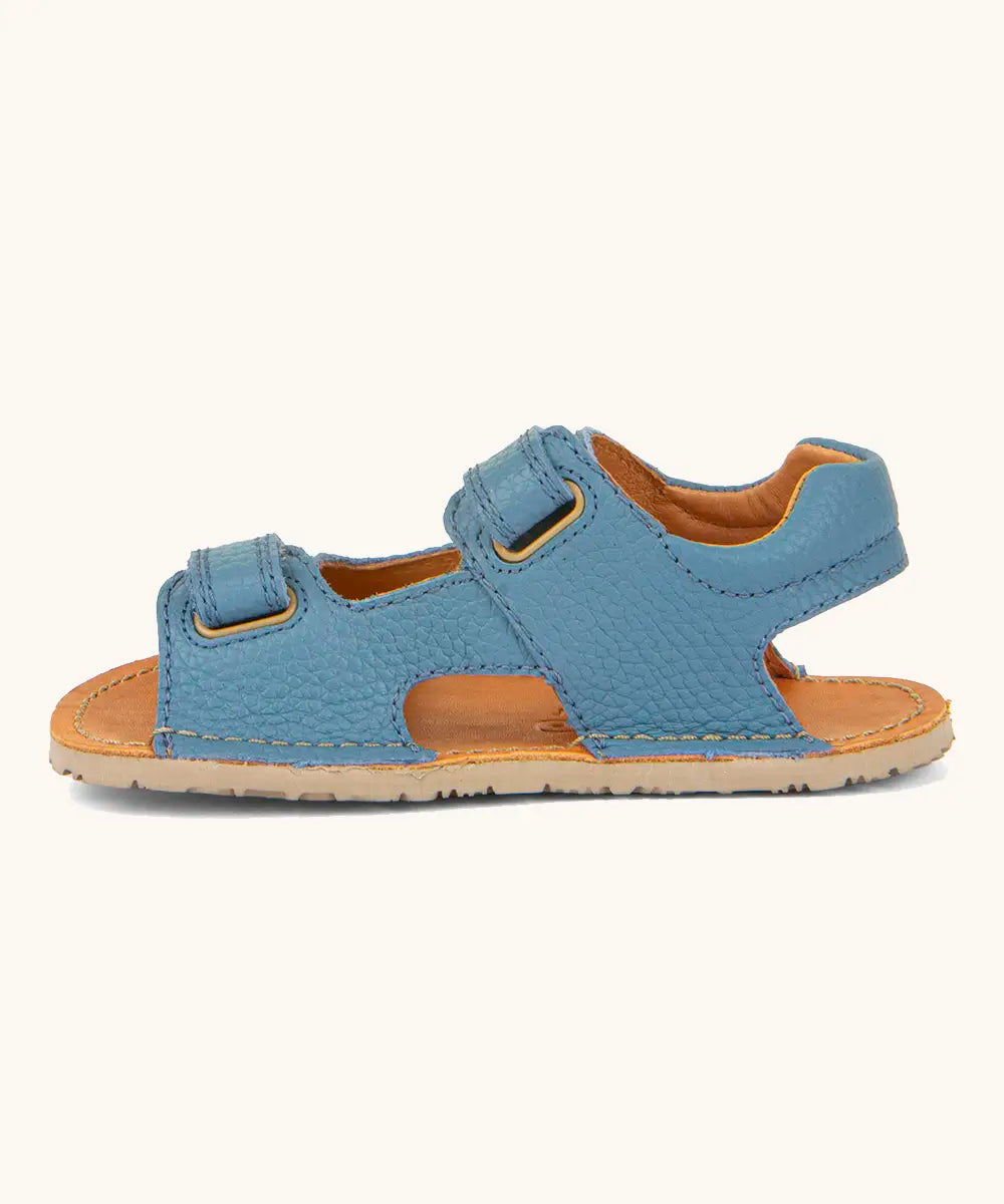 Side of Froddo barefoot kids natural leather sandal in light blue showing velcro straps looped through the eyelets