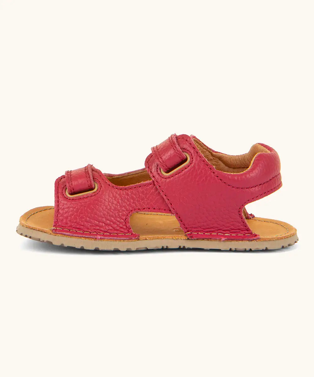 Side of Froddo barefoot kids natural leather sandal in red showing velcro straps looped through the eyelets