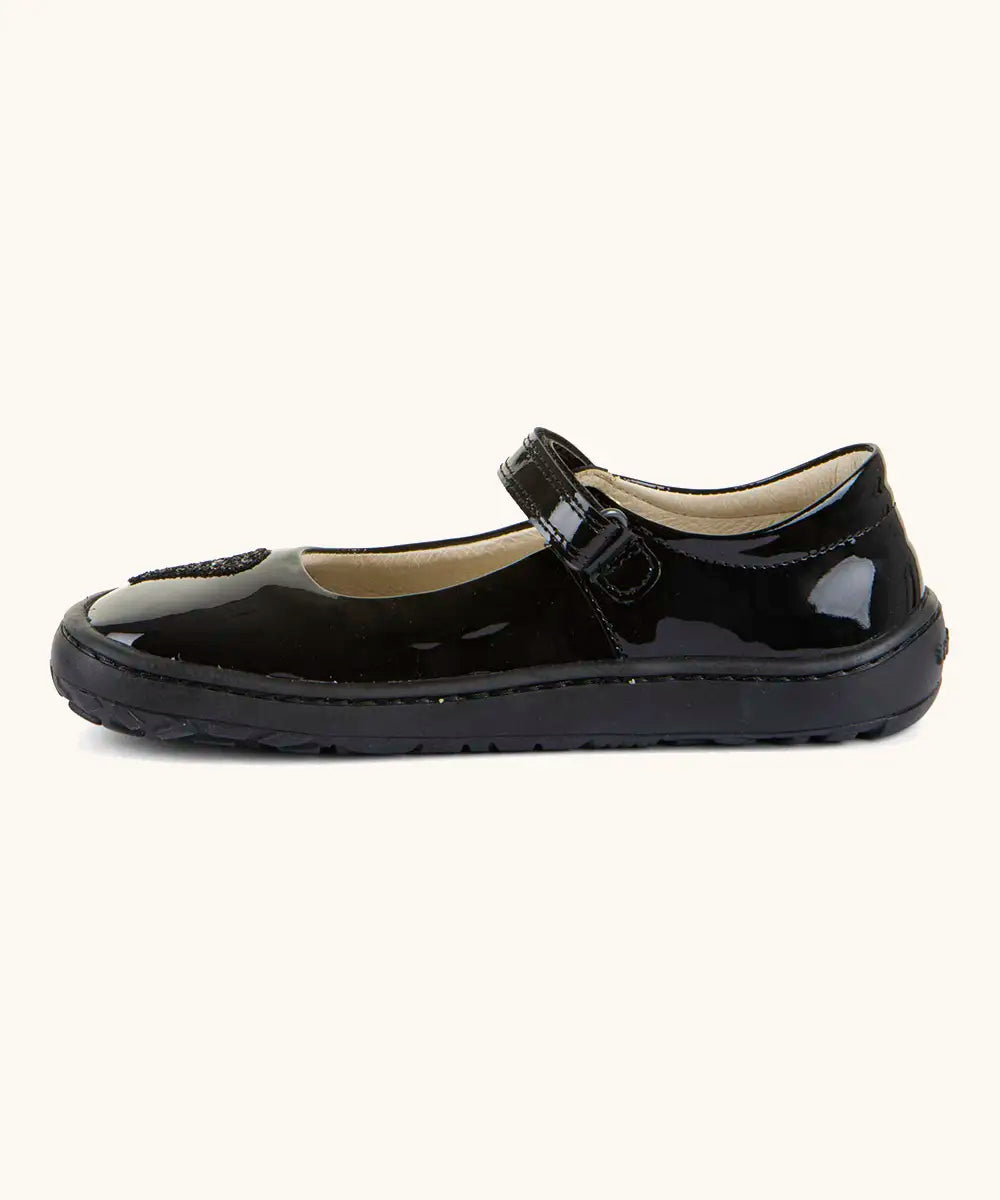 Side of Froddo barefoot kids in black patent school shoe showing velcro strap looped through the eyelet