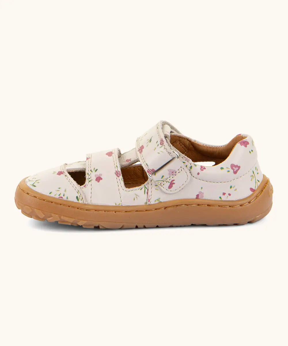 Side of Froddo barefoot children's sandal in pink with flowers showing a velcro fasteners looped through the eyelet