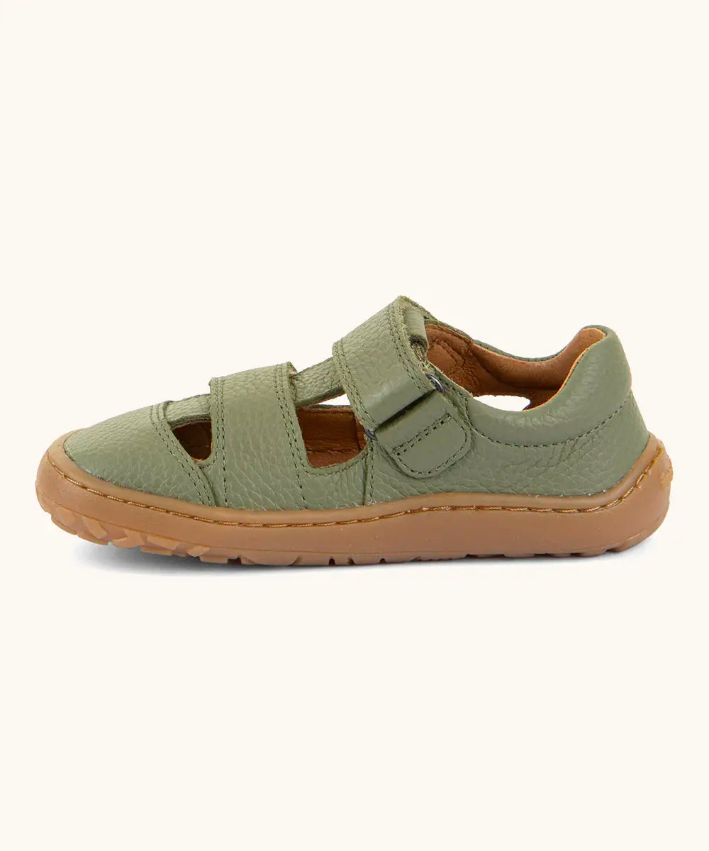 Side of Froddo barefoot children's sandal in green showing a velcro fasteners looped through the eyelet and the brown rubber sole