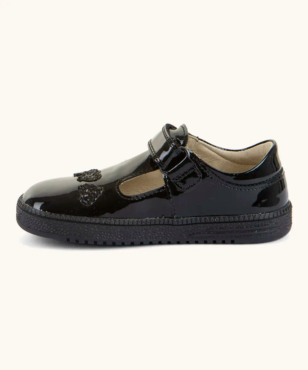 Side of Froddo barefoot kids school shoe in black patent material showing t-bar velcro fastener looped through eyelet