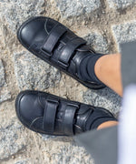 Child wearing Froddo's natural black leather barefoot school shoes showing the 2 front velcro fasteners