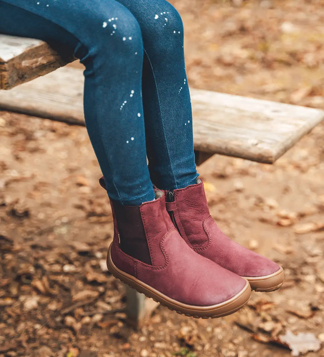 Child wearing Froddo's barefoot kids leather chelsea boot in maroon. Boots sit above the ankle and have a zip fastener