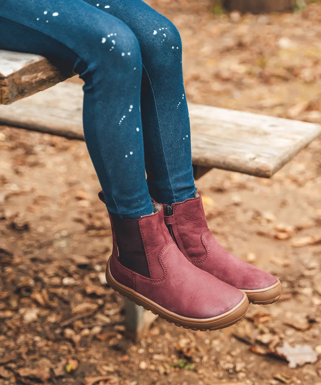 Child wearing Froddo's barefoot kids leather chelsea boot in maroon. Boots sit above the ankle and have a zip fastener