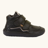 Side of Froddo barefoot tex kids autumn natural leather ankle school boots in black showing Velcro straps fully fastened and brown flexible rubber sole