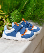 Pair of Froddo barefoot zeru Spring kids shoes in blue and white on a stone surface with plants in the background