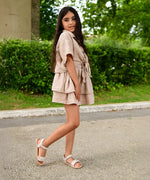 Child wearing Froddo's barefoot kids natural leather lia sandals in pink with flowers on a concrete surface outdoors