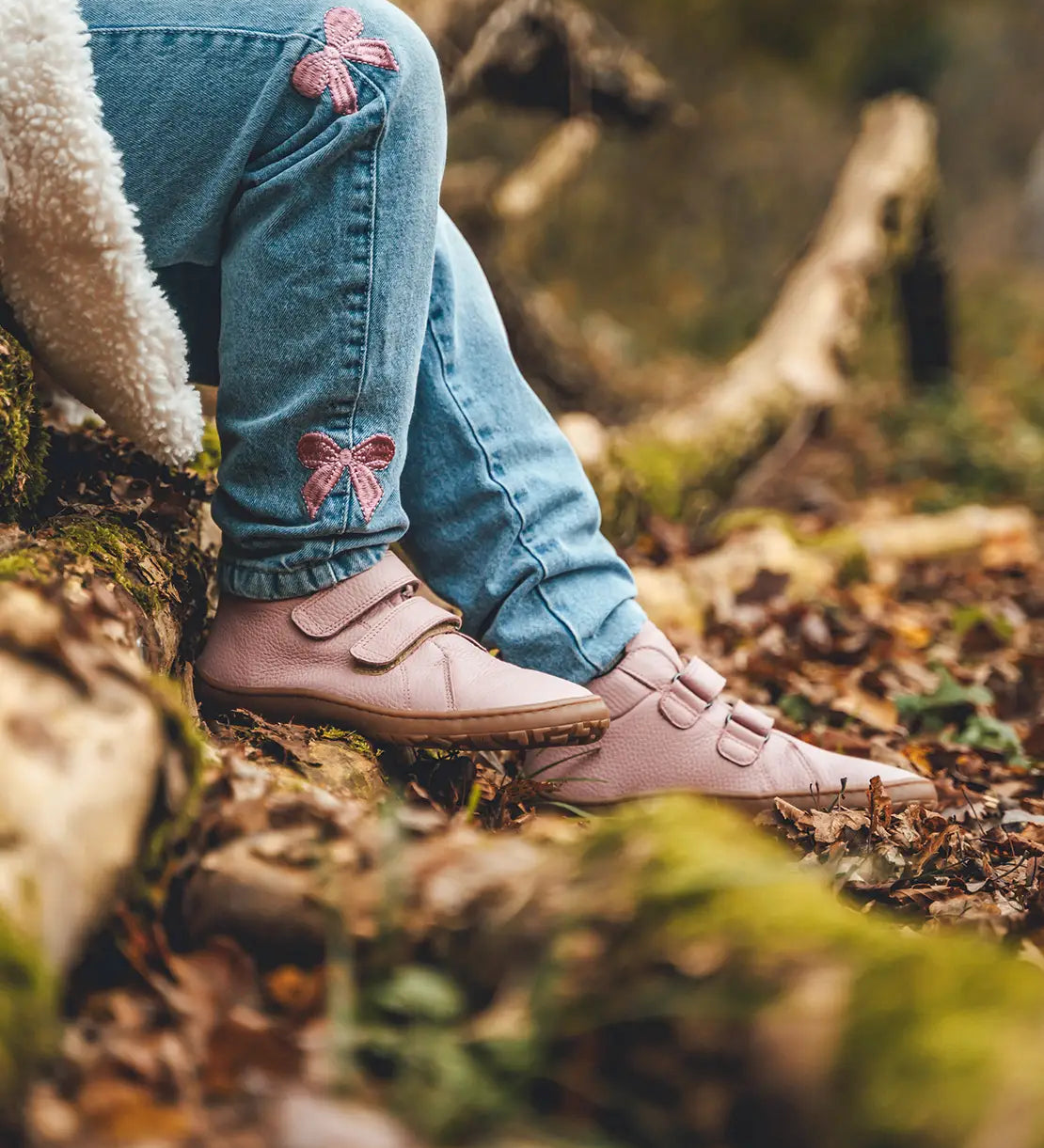 Child wearing Froddo natural leather kids barefoot shoe in pink in the forest. Hi-top boot has a flexible brown rubber sole and wide toe box